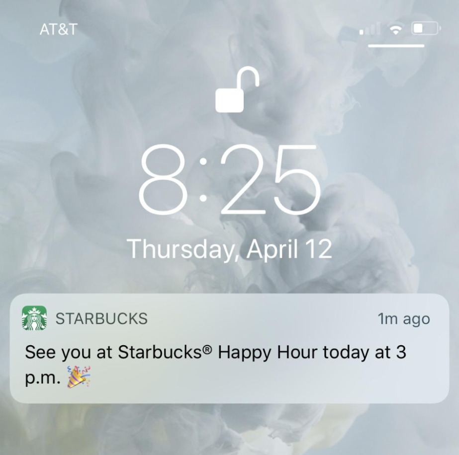 A screenshot of an iPhone lock screen with an AT&T signal and a notification at 8:25 on Thursday, April 12. The notification is from STARBUCKS, reading: "See you at Starbucks® Happy Hour today at 3 p.m. 🎉". The background is a smoke-like white and yellow pattern. The camera and flashlight icons are visible at the bottom.
